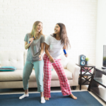 To jenter som danser foran TV i en stue.